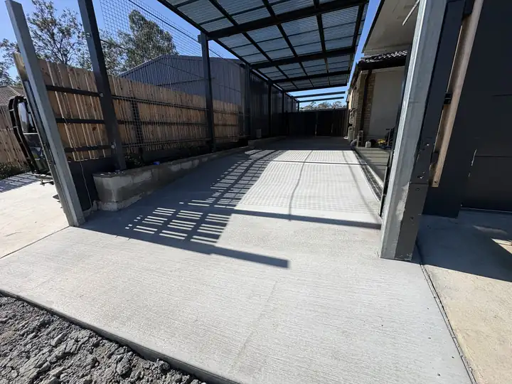 Broom finished concrete running under a carport and along a side fence in Brisbane